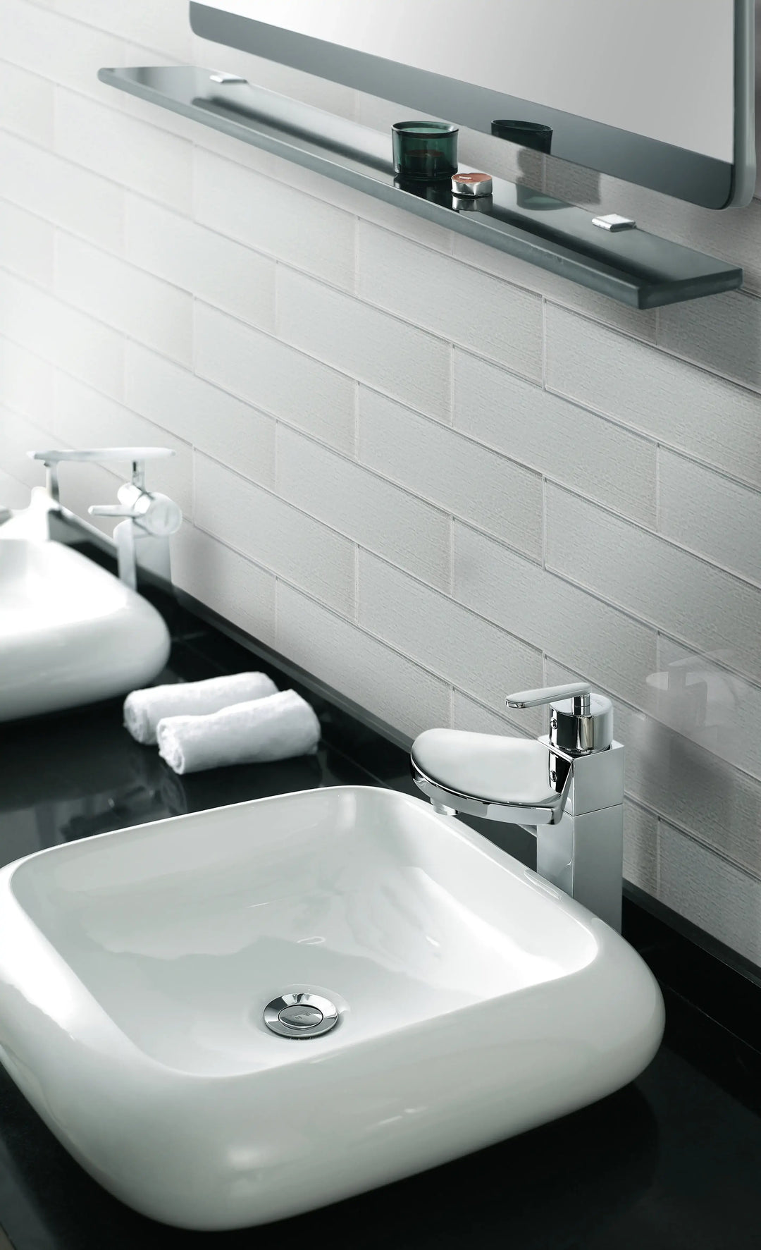 Modern bathroom with white square sink, chrome faucet, and glass backsplash tiles, reflecting a minimalist luxurious design.
