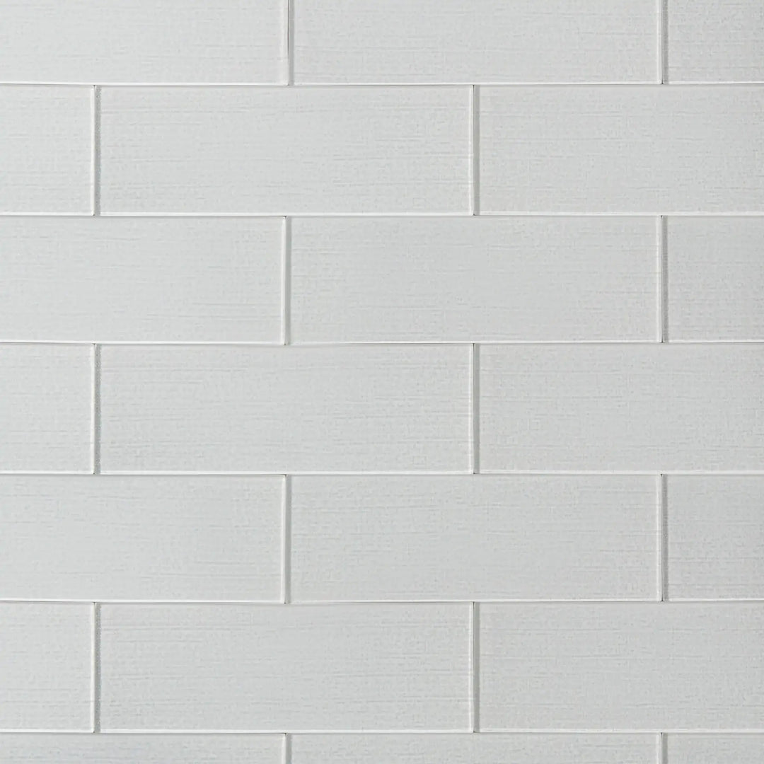 Linen ice 4-in x 12-in glass wall tiles with reflective surface, ideal for modern kitchen backsplashes and bathroom walls.
