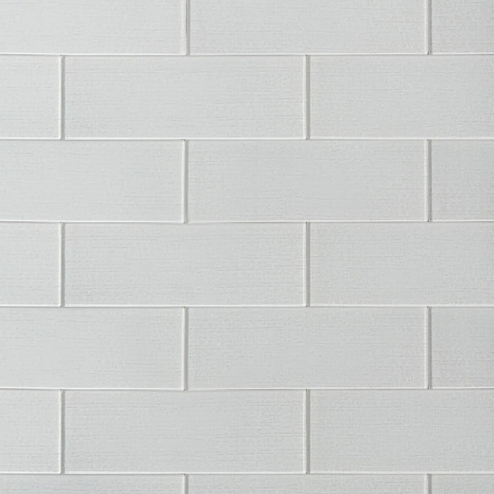 Linen ice 4-in x 12-in glass wall tiles with reflective surface, ideal for modern kitchen backsplashes and bathroom walls.